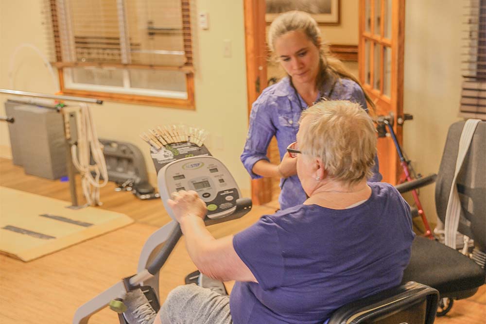 Person doing physical therapy with older woman